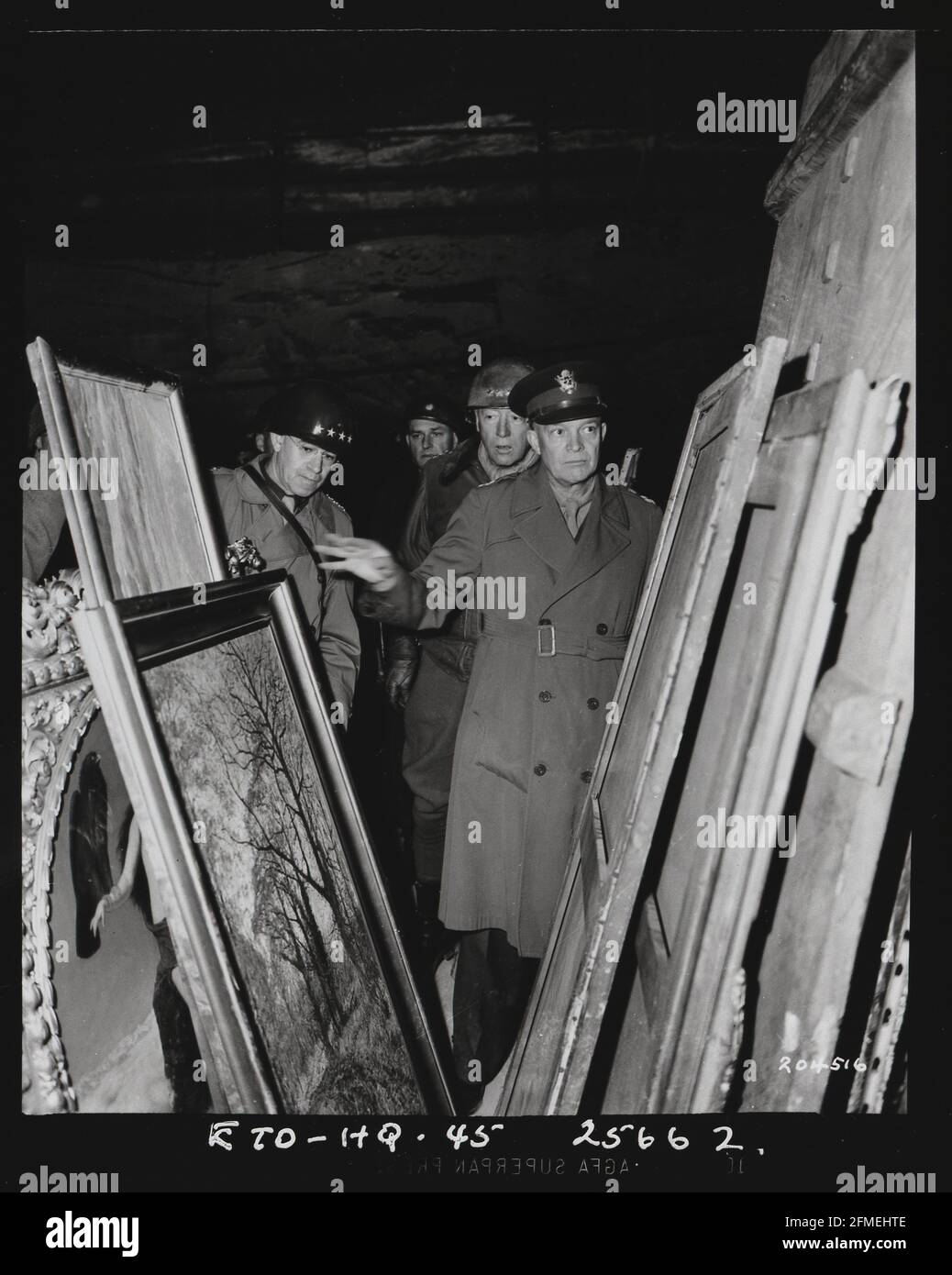 Pendant la Seconde Guerre mondiale, le général Dwight D. Eisenhower inspecte les peintures dans une mine de sel à Merkers, près de Gotha, en Allemagne, où le gouvernement nazi stockait des trésors d'art et de l'or, pillées dans les pays occupés, le 12 avril 1945. Le Commandant suprême des forces alliées était accompagné du général Omar N. Bradley, à gauche, et du Lieutenant général George Patton Jr., immédiatement derrière lui. Plus de 20 pour cent de l'art européen a été pillé par les nazis sous Hitler, et jusqu'à 100,000 œuvres sont encore considérées comme disparues. Banque D'Images