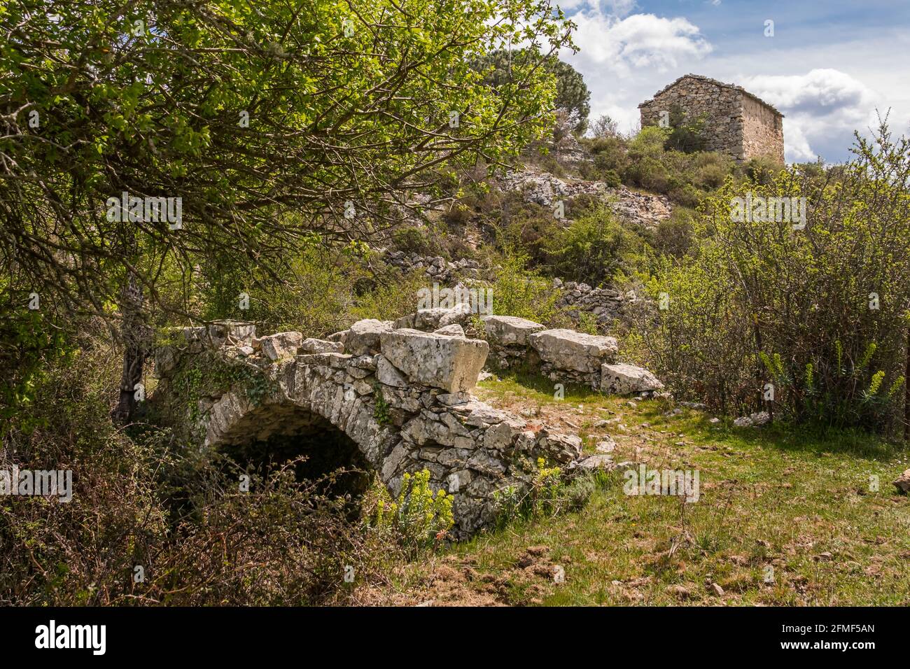Un petit pont Genoise au-dessus d'un ruisseau dans la Balagne Région de Corse avec une ancienne ferme en pierre la distance Banque D'Images