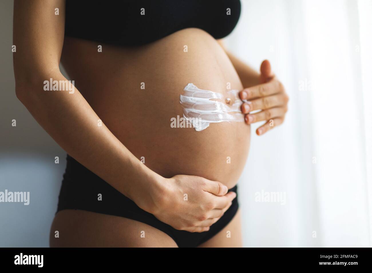 Femmes enceintes mettant la crème anti-étirement sur son ventre. Cosmétique pour hydrater ou hydrater la peau pendant la grossesse. Banque D'Images
