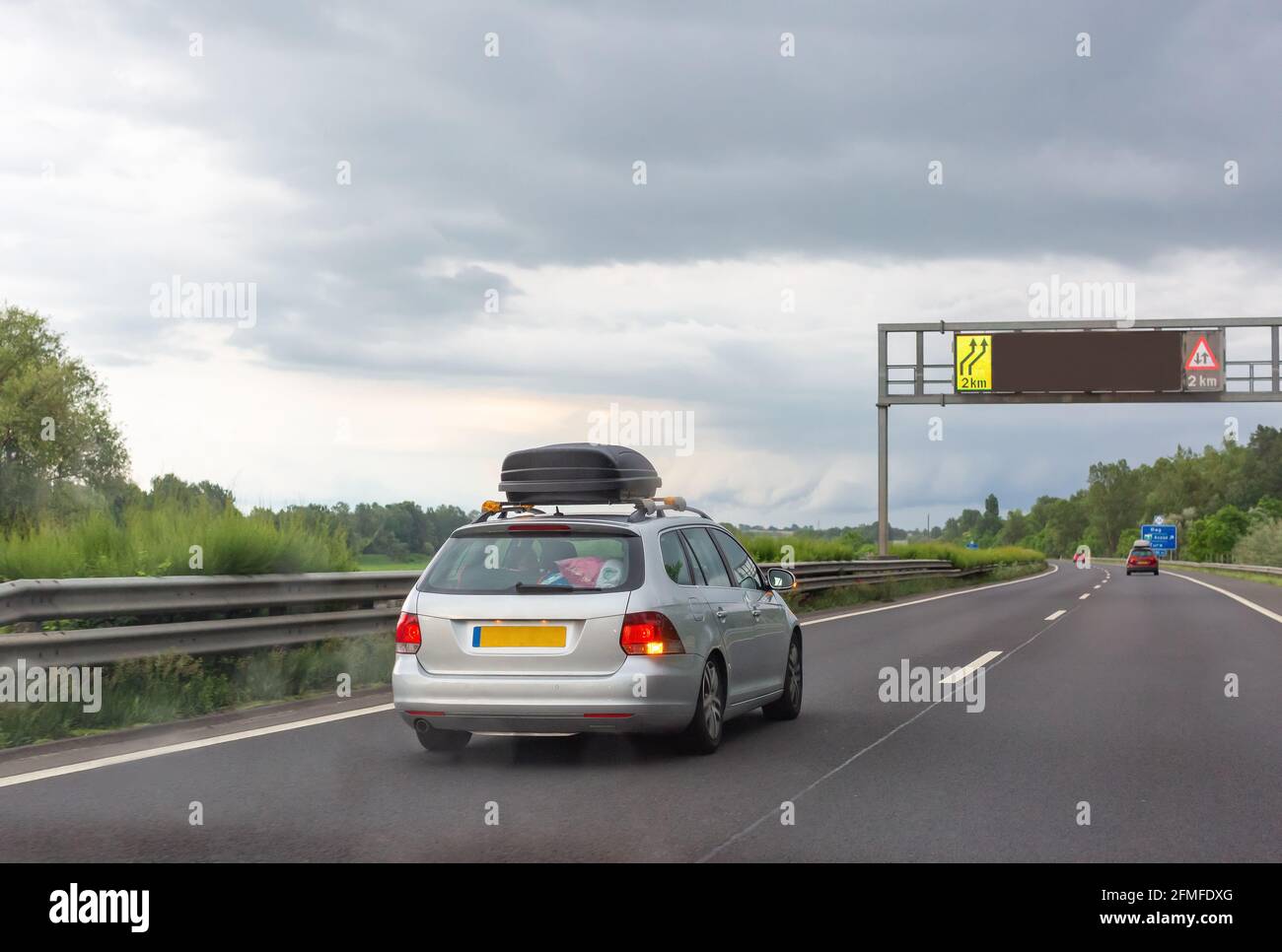 Voiture argent avec coffre à bagages de toit noir roulant sur le route Banque D'Images