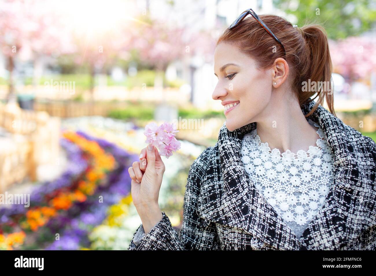 Bonne jeune femme caucasienne à tête rouge portant un portrait en fleur de cerisier rose Banque D'Images