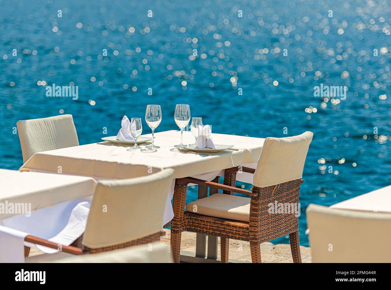Un café de rue vide en mer à Perast, au Monténégro. Table et chaises au bord de l'eau. Détendez-vous et voyagez à Balcans, en Europe. Banque D'Images