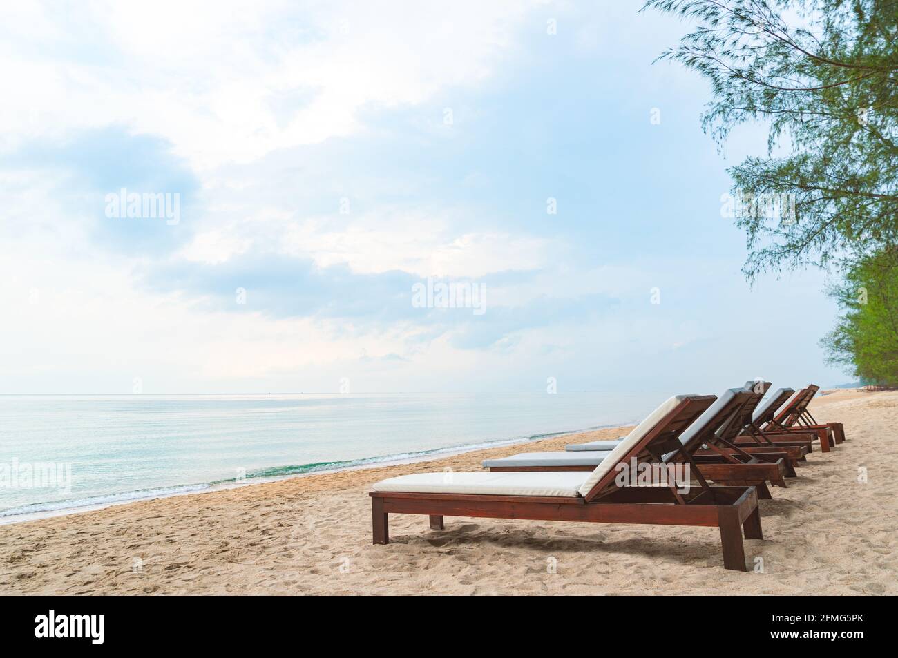 Plage en bois lit ou plage avec chaises longues sur une belle plage avec l'océan turquoise et le ciel bleu, pas de personnes, vue perspective avec espace pour copier sur le ciel, image o Banque D'Images