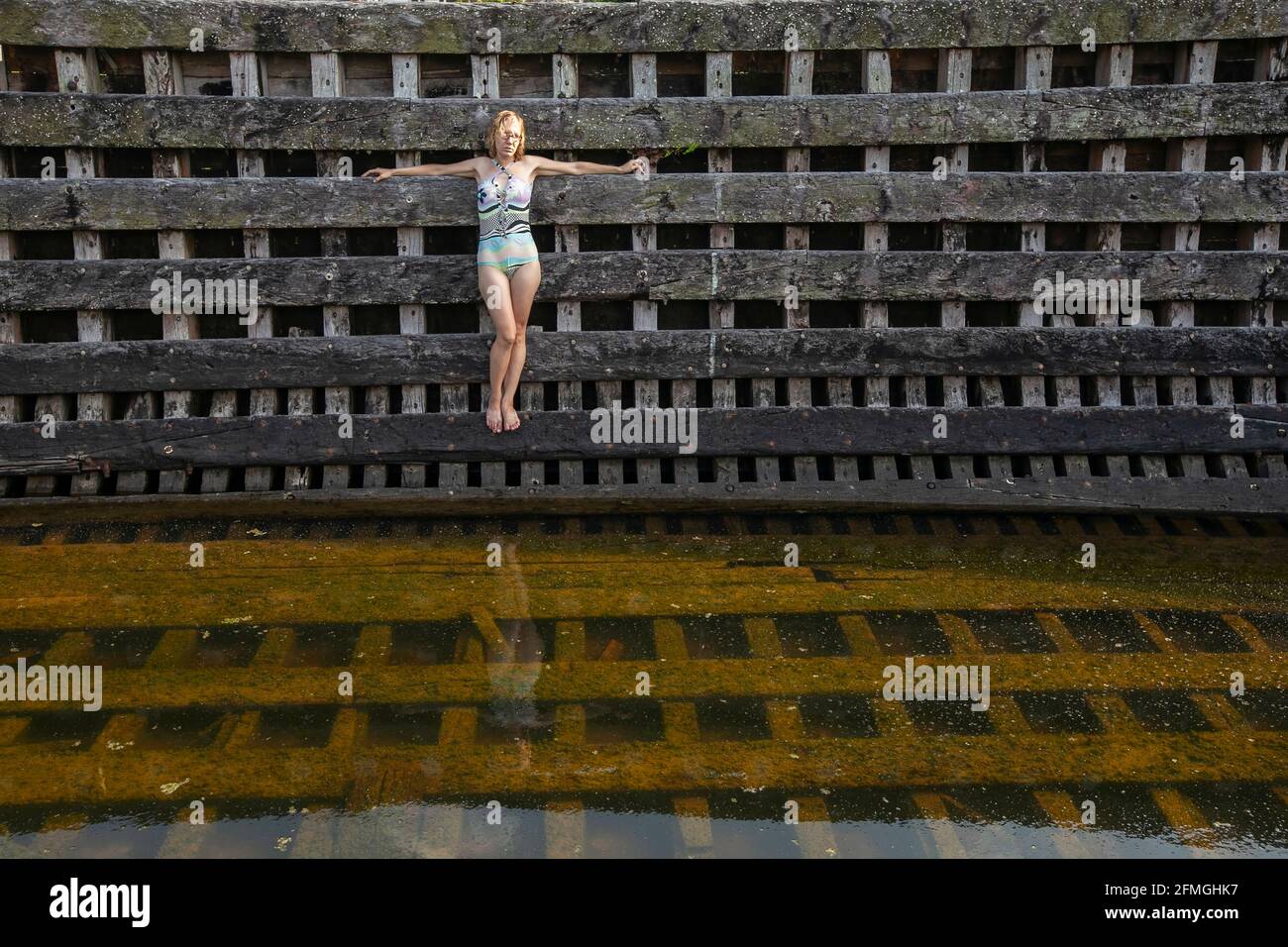 Une jeune femme en maillot de bain se tient à bord d'un bateau en bois abandonné. Banque D'Images