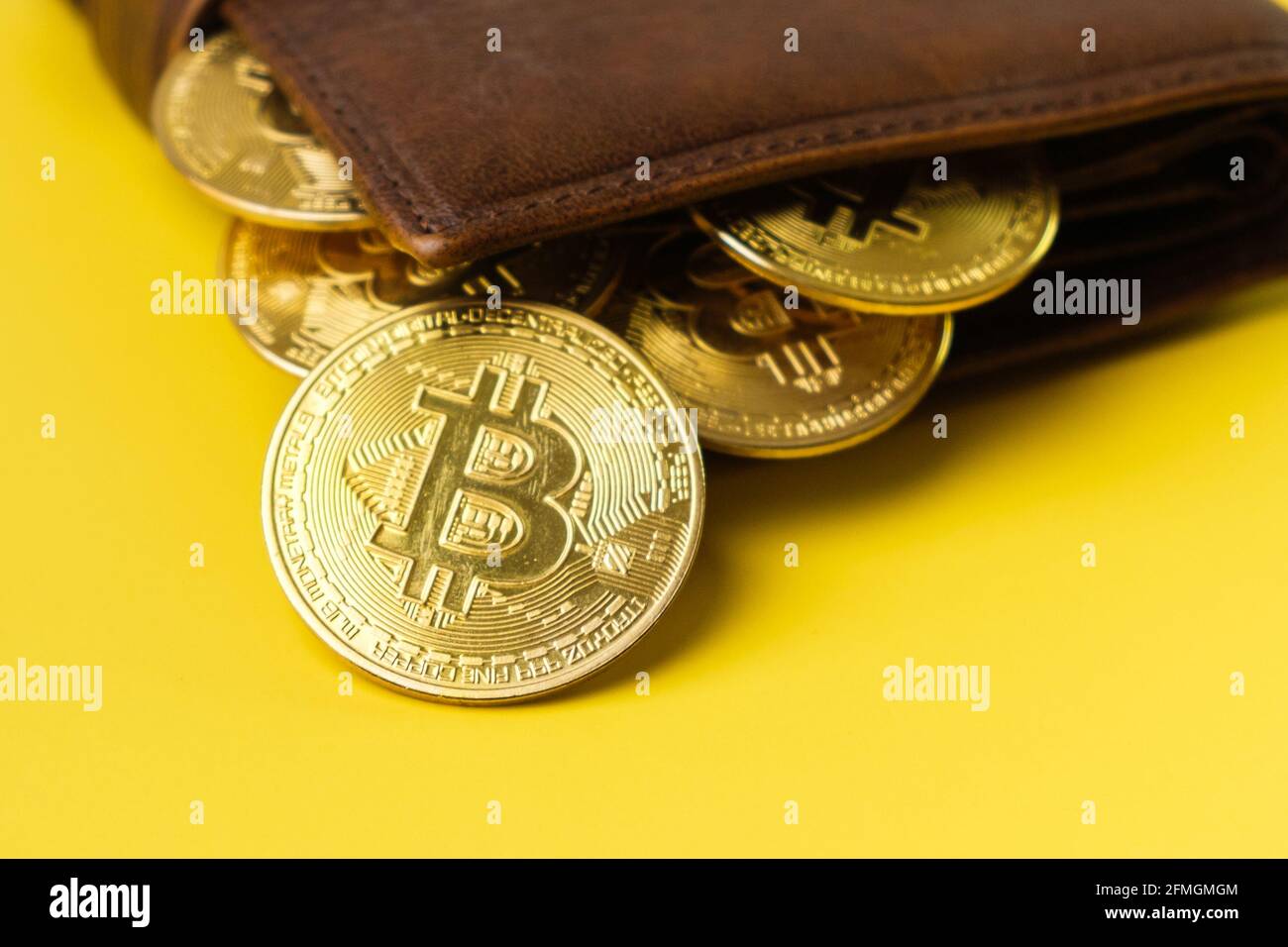 Pièces de monnaie en bitcoin dans le portefeuille sur fond jaune. Banque D'Images