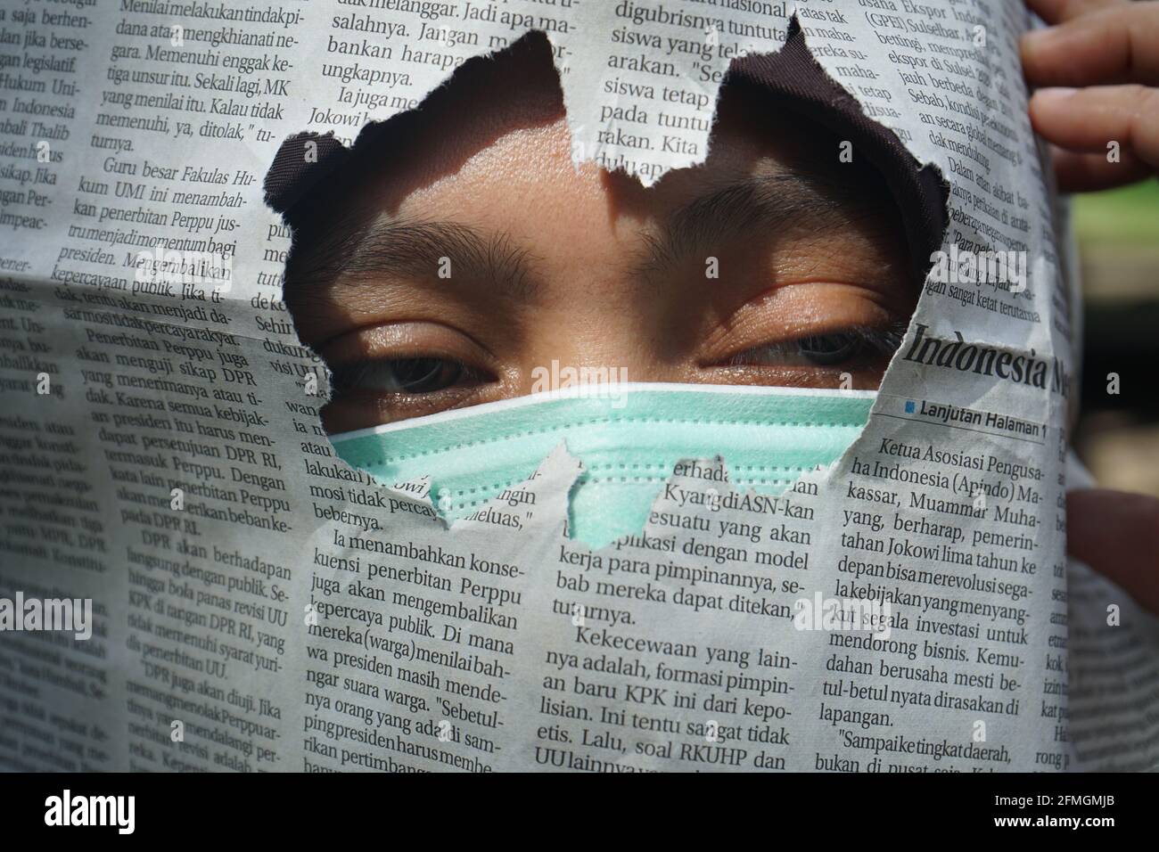 Une femme portant un masque avec un journal déchiré dedans avant Banque D'Images