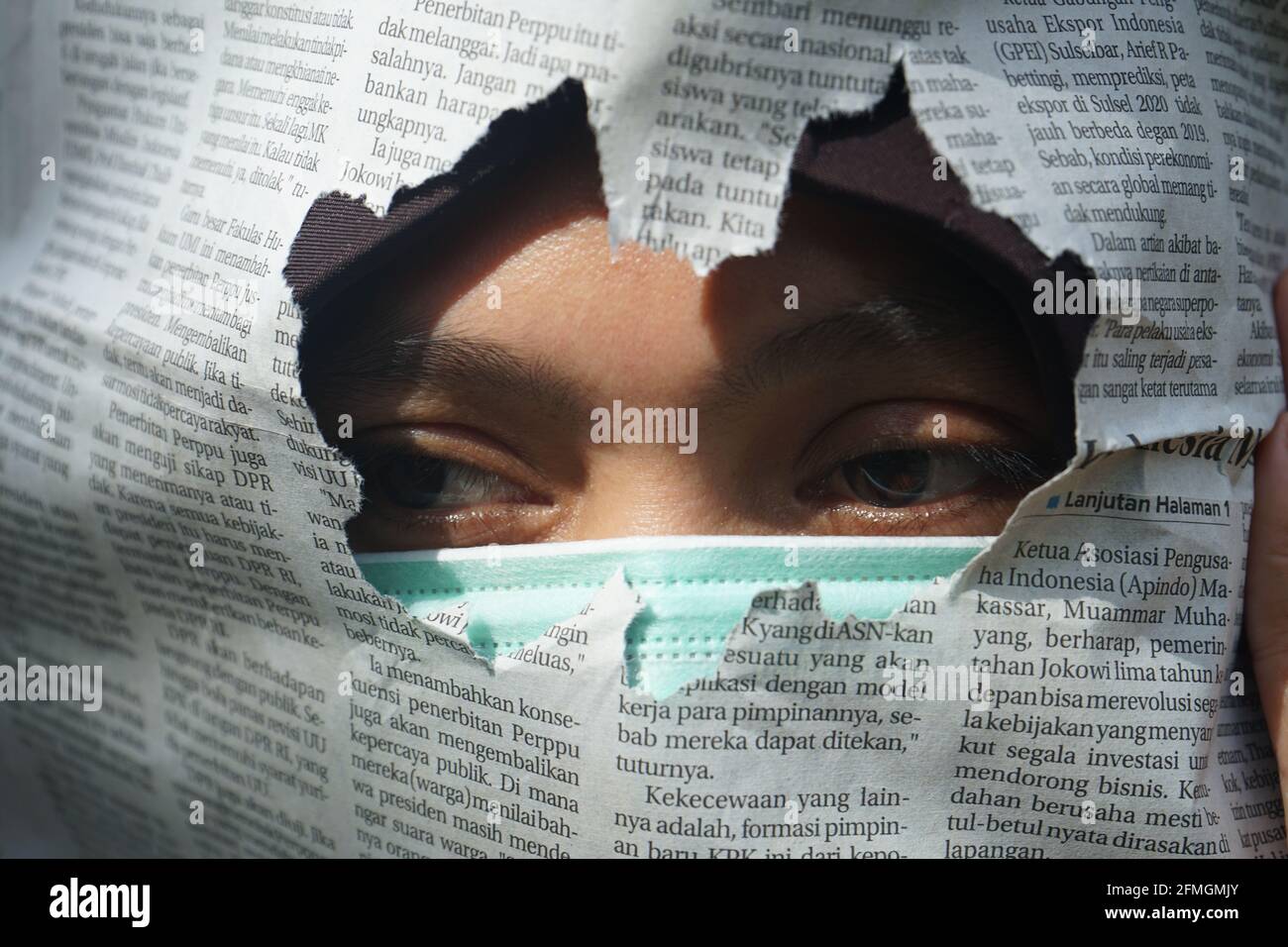 Une femme portant un masque avec un journal déchiré dedans avant Banque D'Images