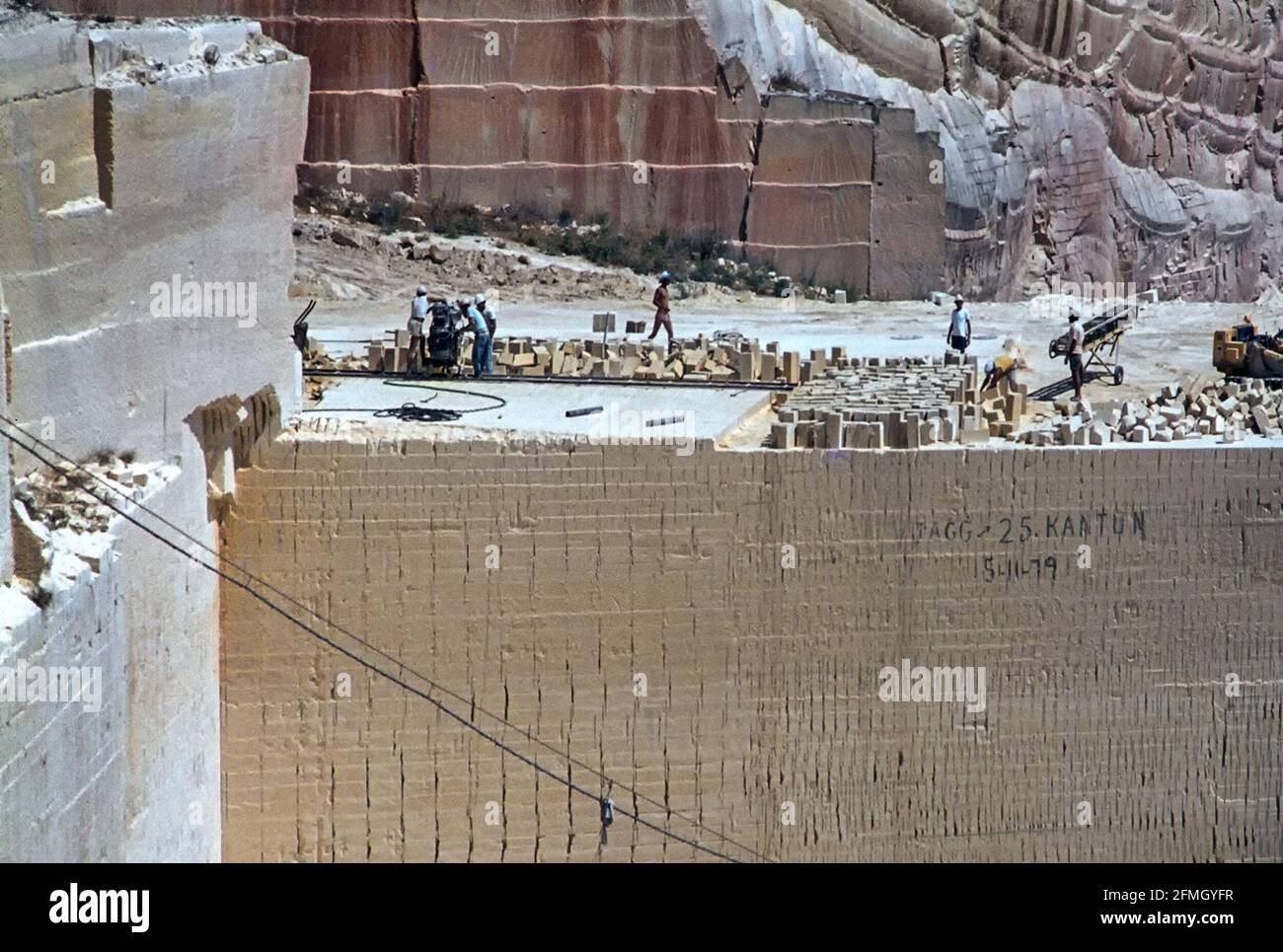 Vue des archives des années 1980 des travailleurs maltais de la mine de surface travaillant au-dessus de la chute de cisaillement de la face non protégée de la fonte calcaire ouverte carrière avec des problèmes de santé et de sécurité après des années d'utilisation de la scie à disque de coupe de machines scier dans la roche molle à être tranché en blocs pour les chantiers de construction des années 80 sur l'île de Malte en image d'archives historiques juin 1981 Banque D'Images