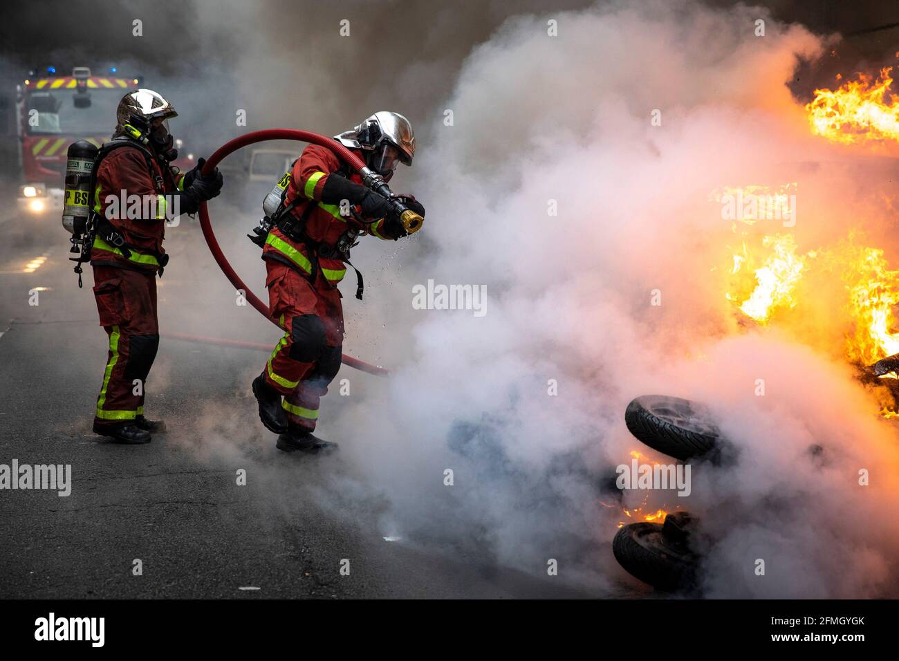 Les pompiers se préparent à éteindre les flammes d'un véhicule et d'un scooter qui a été mis en feu sur une route près de la Arc de Triomphe le quatrième samedi o Banque D'Images