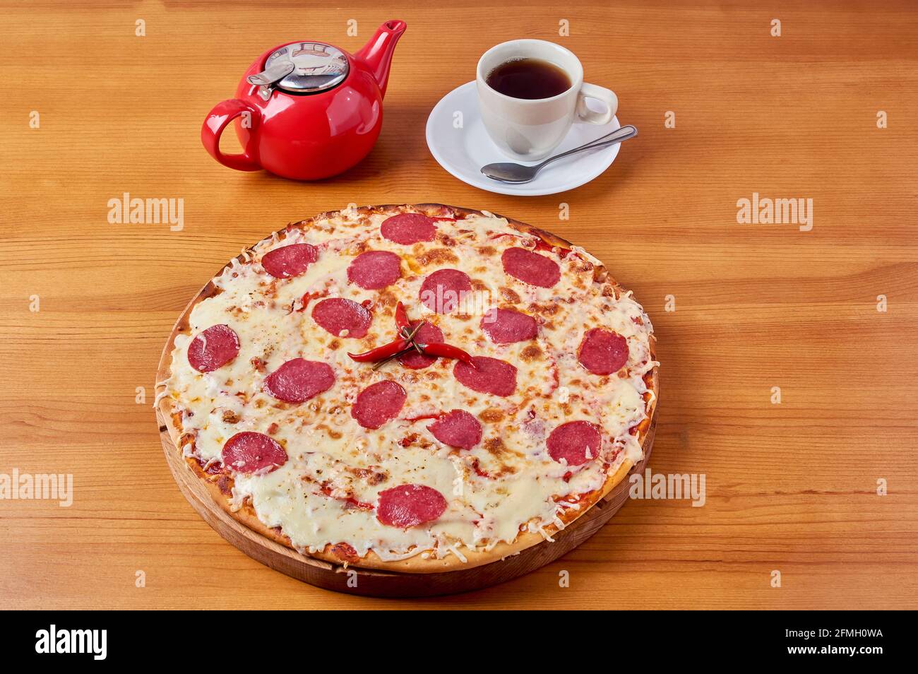 pizza italienne au poivre rouge sur un support en bois avec thé et bouilloire Banque D'Images