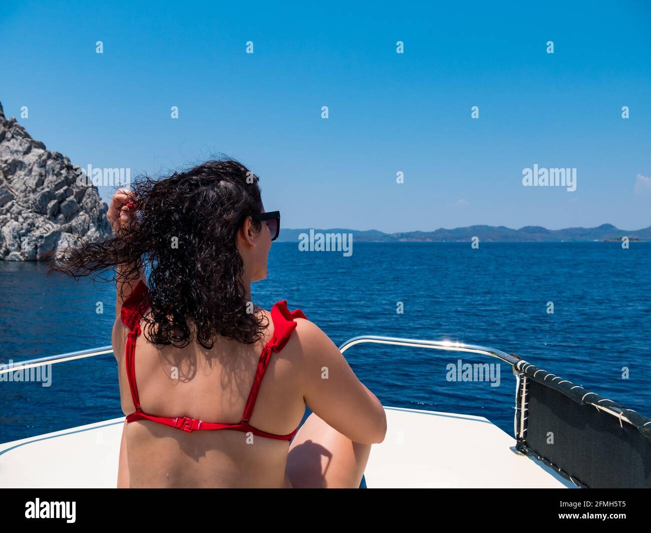 Vue depuis l'arrière de la belle femme assise sur la terrasse du bateau. Concept de vacances en mer d'été. Copier l'espace Banque D'Images
