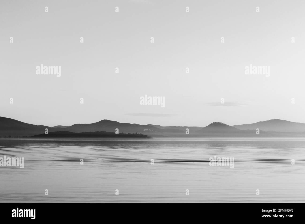 Vue sur le lac Trasimeno en Ombrie, Italie, avec un ciel vide et de magnifiques reflets d'eau avec des ondulations. Immobilité extra-terrestre. Banque D'Images