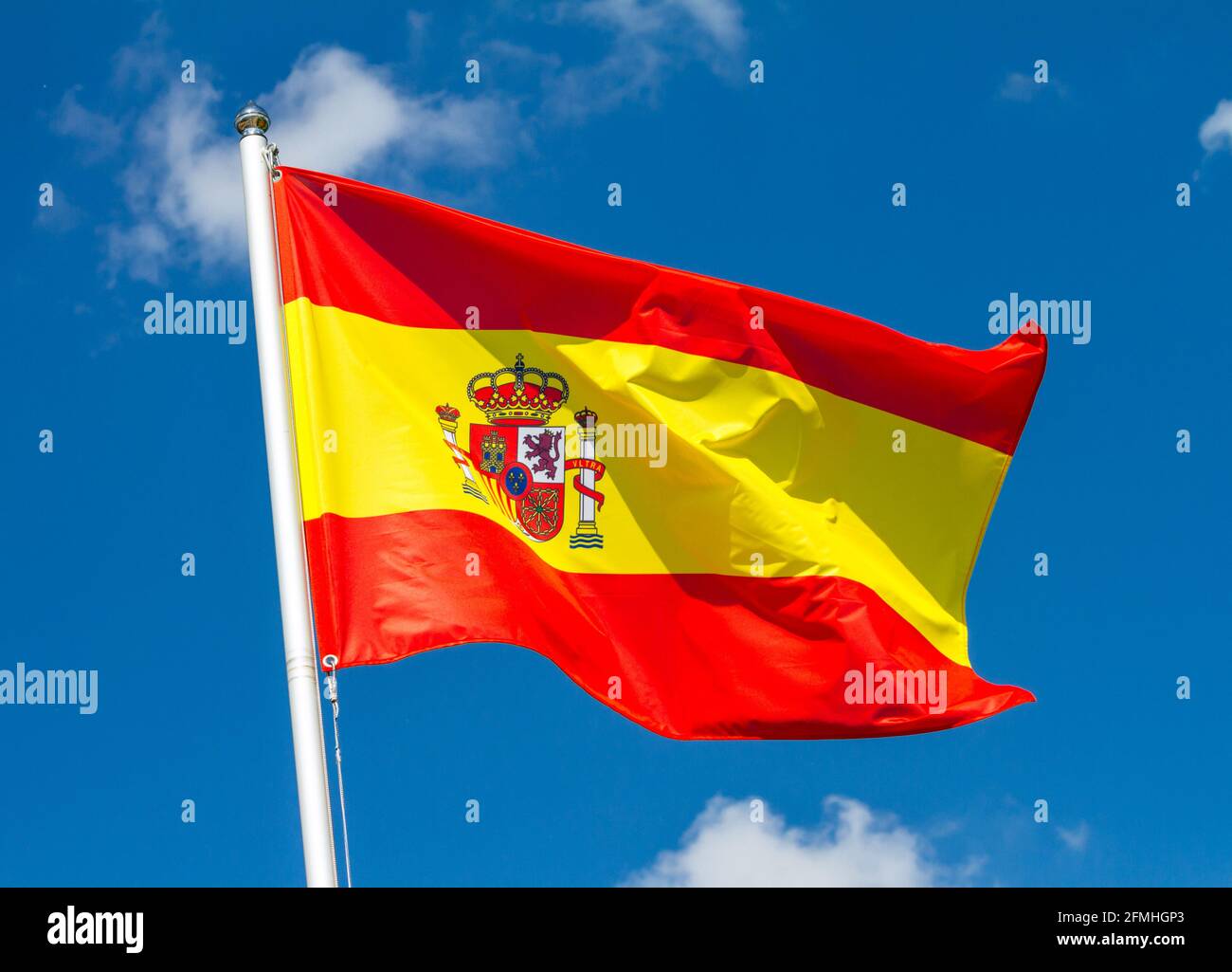 Drapeau de l'Espagne agitant dans le vent sur le mât contre le ciel avec des nuages le jour ensoleillé, gros plan Banque D'Images