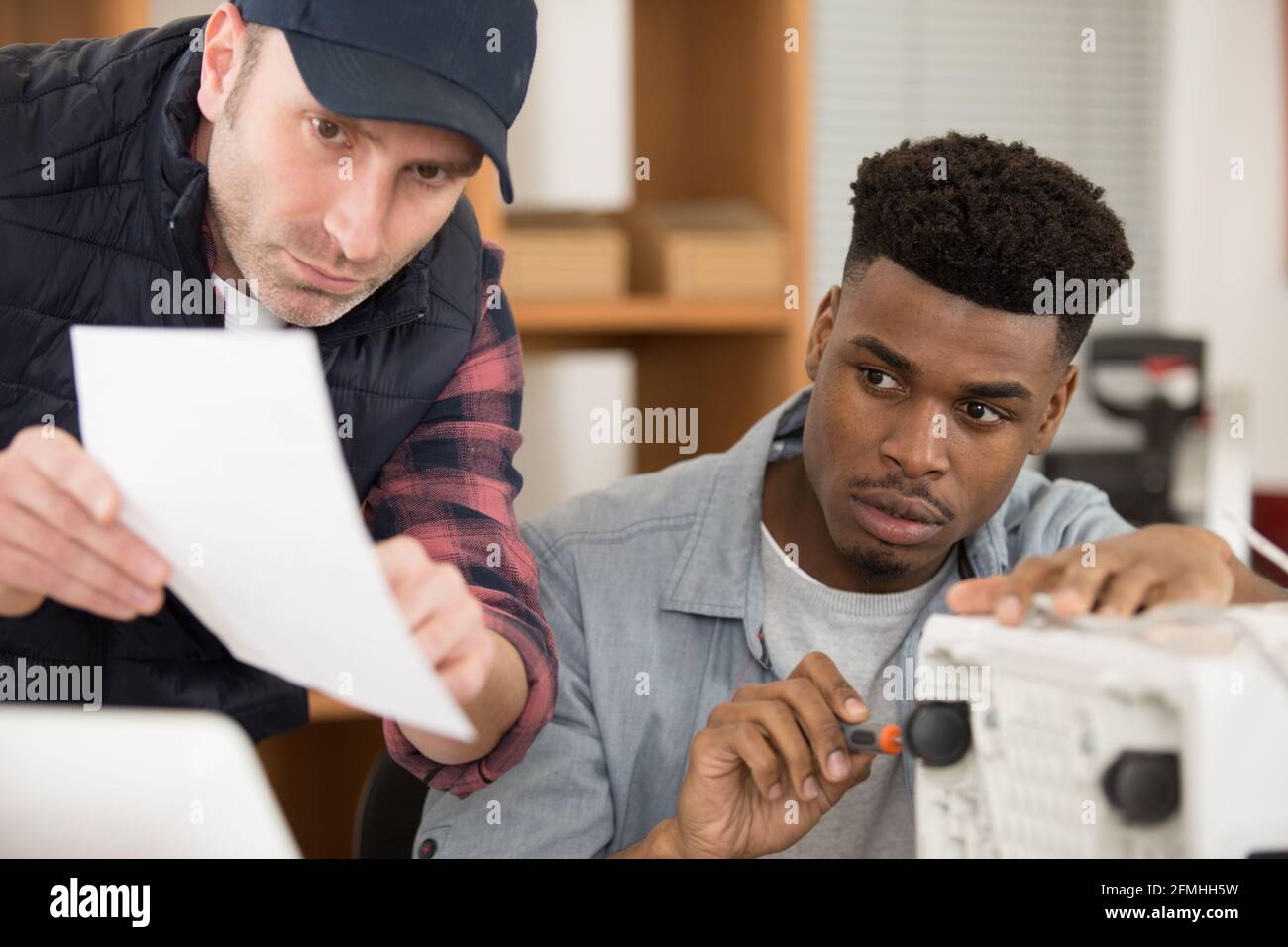 les ouvriers suivent les instructions de montage d'un appareil électrique Banque D'Images