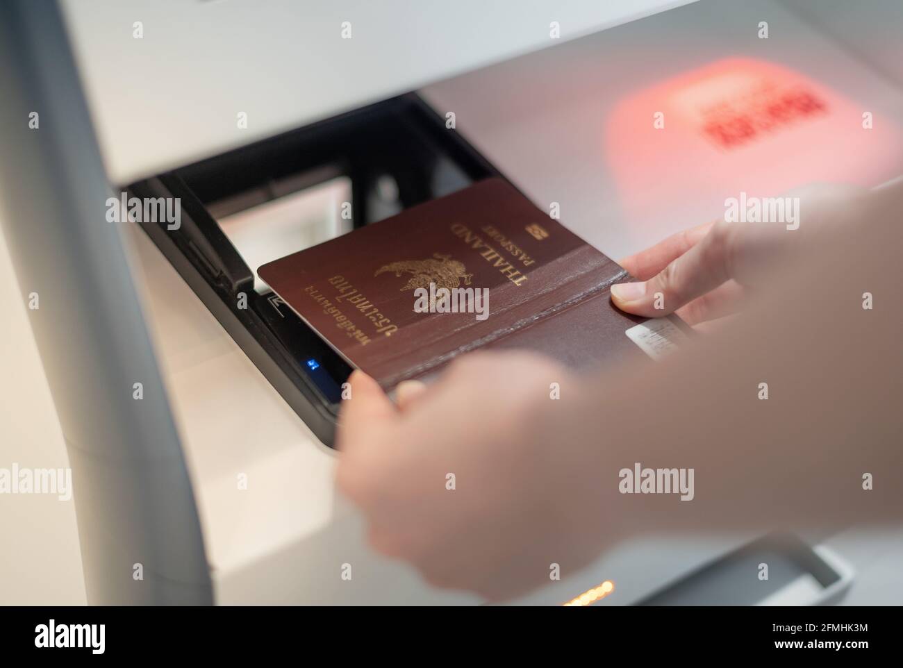 Une femme tient la main avec un lecteur de passeport personnel au comptoir d'enregistrement en libre-service pour obtenir une carte d'embarquement au terminal de l'aéroport. Banque D'Images