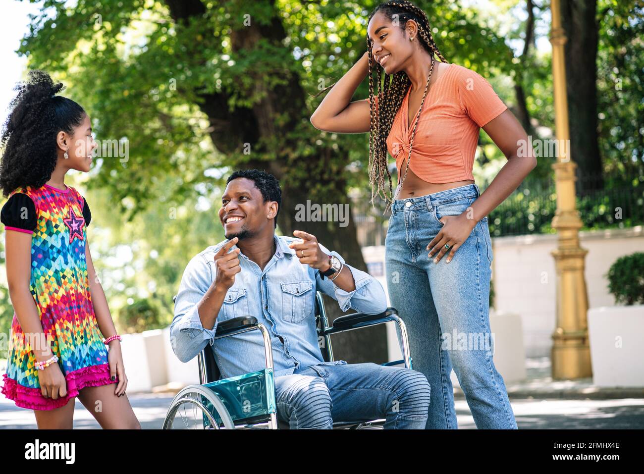 Homme en fauteuil roulant appréciant avec sa famille à l'extérieur. Banque D'Images