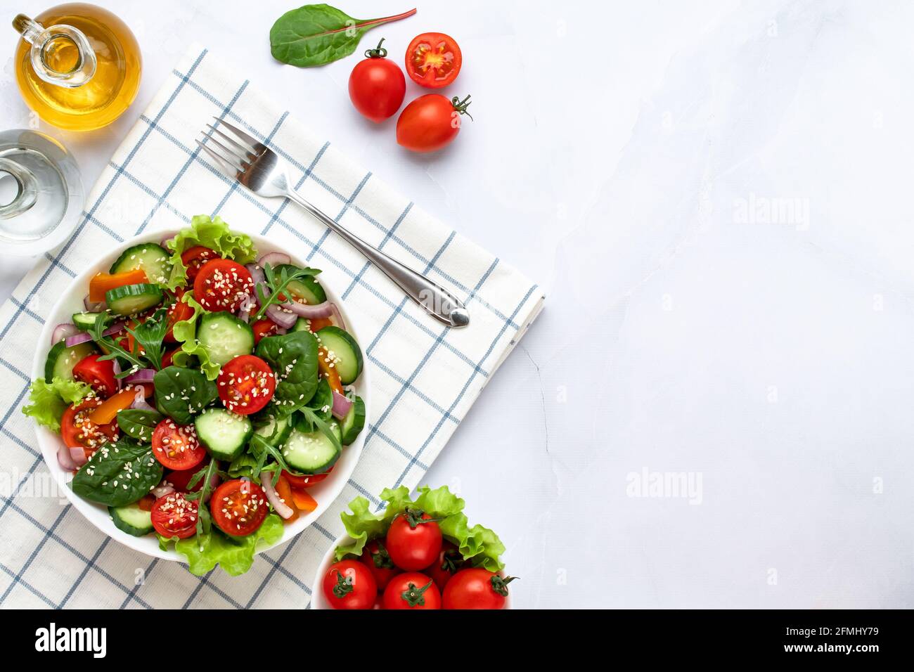 Salade composée de morceaux de tomates, concombres, oignons, tranches de poivron, arugula, sésame, basilic et huile d'olive. Concept d'alimentation saine, a v Banque D'Images