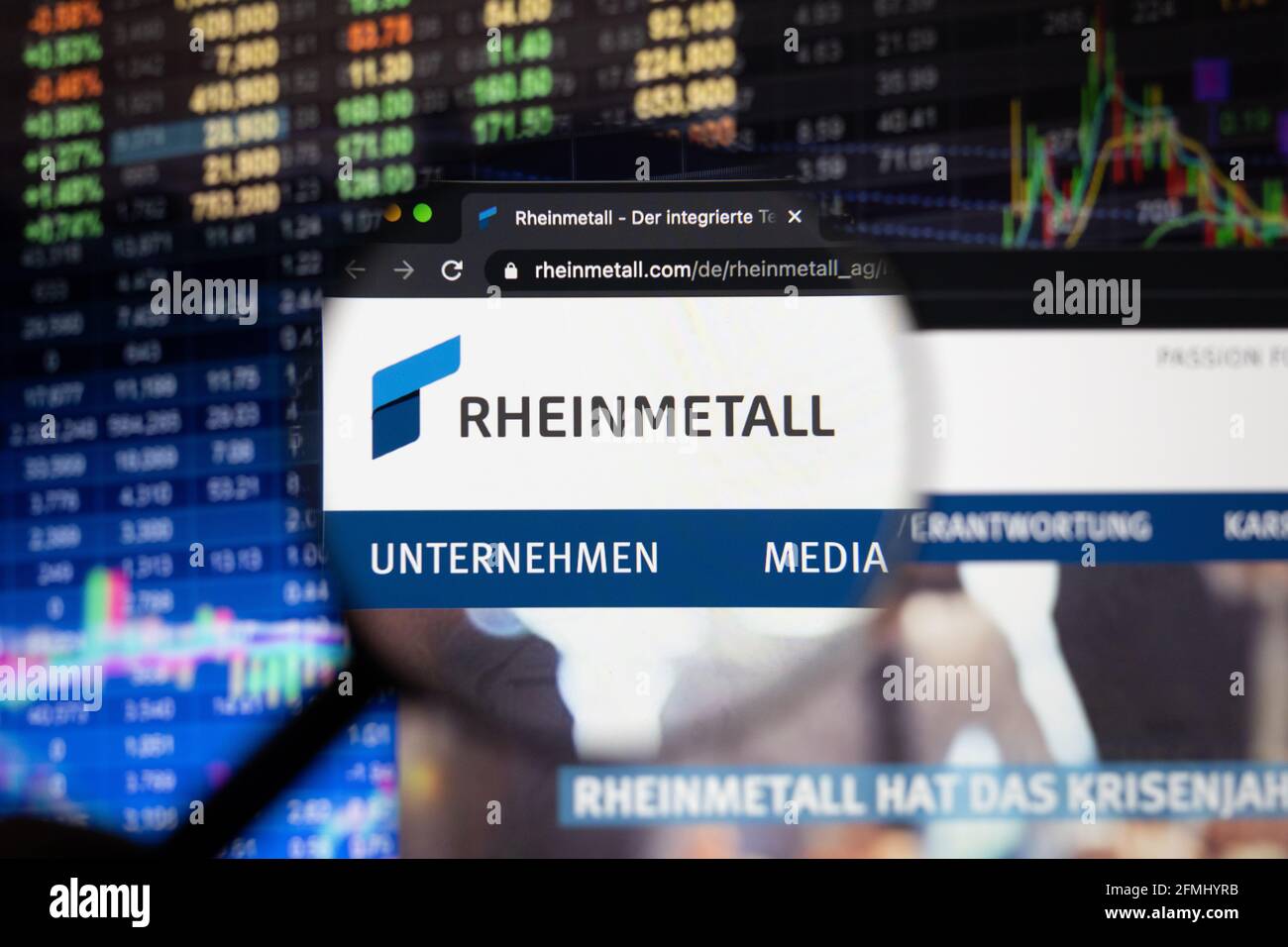 Logo de la société Rheinmetall sur un site web avec des développements flous du marché boursier en arrière-plan, vu sur un écran d'ordinateur à travers une loupe Banque D'Images
