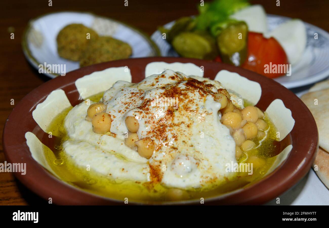 Houmous servis avec du pain pita et des légumes. La sauce épicée peut être ajoutée à ce favori du Moyen-Orient. Banque D'Images