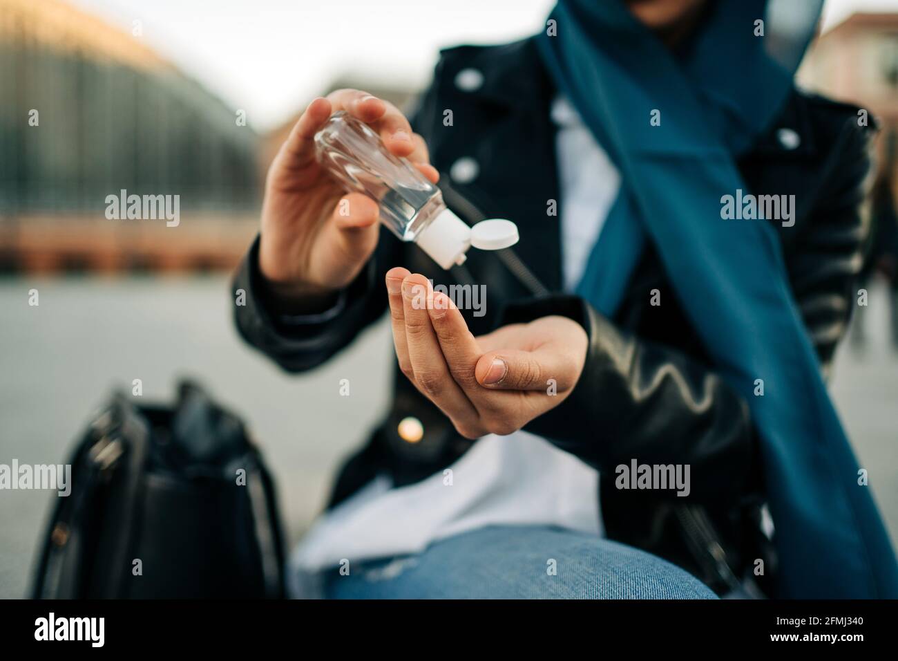 Récolte de la femme musulmane méconnaissable dans le hijab appliquant un désinfectant antibactérien sur mains dans la rue de la ville pendant la pandémie du coronavirus Banque D'Images