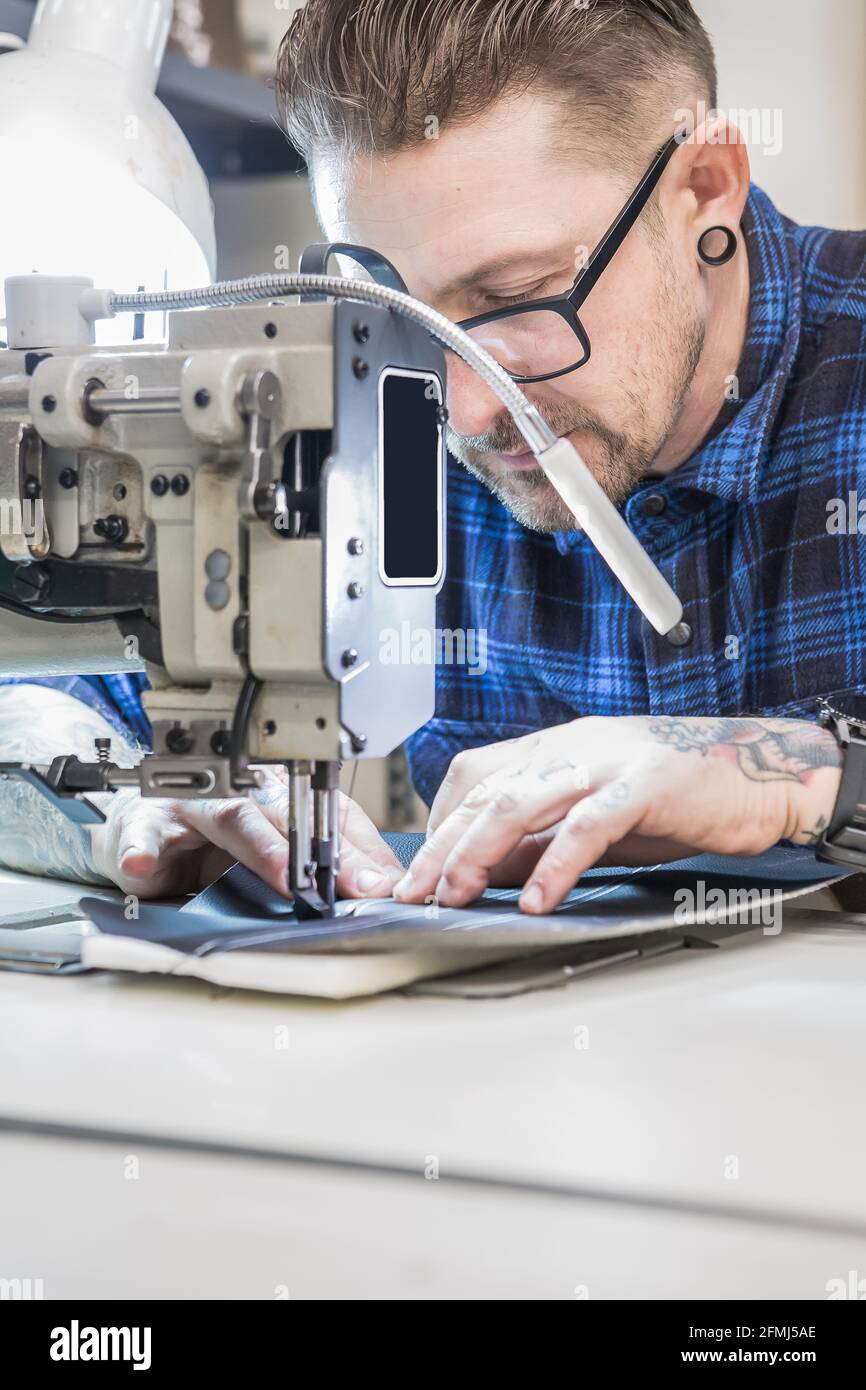 Homme artisan utilisant la machine à coudre tout en créant des tissus d'ameublement pour moto siège dans l'atelier Banque D'Images