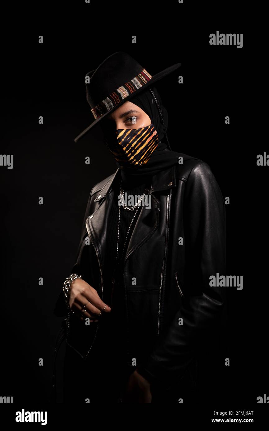 Femme islamique tendance portant une veste en cuir hijab et un chapeau  tendance debout regardant la caméra dans un studio sombre pendant  l'épidémie de coronavirus Photo Stock - Alamy