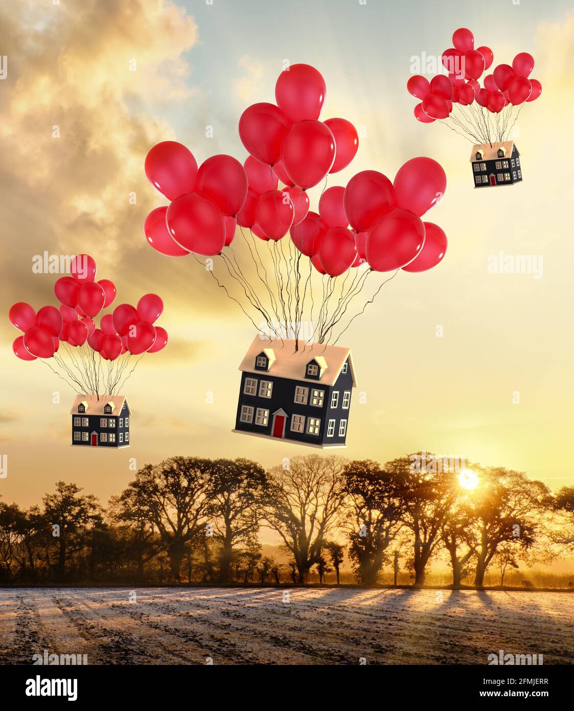 Maisons de jouets attachées à des ballons rouges volant au-dessus des champs ruraux. Passage au pays et aux concepts immobiliers Banque D'Images