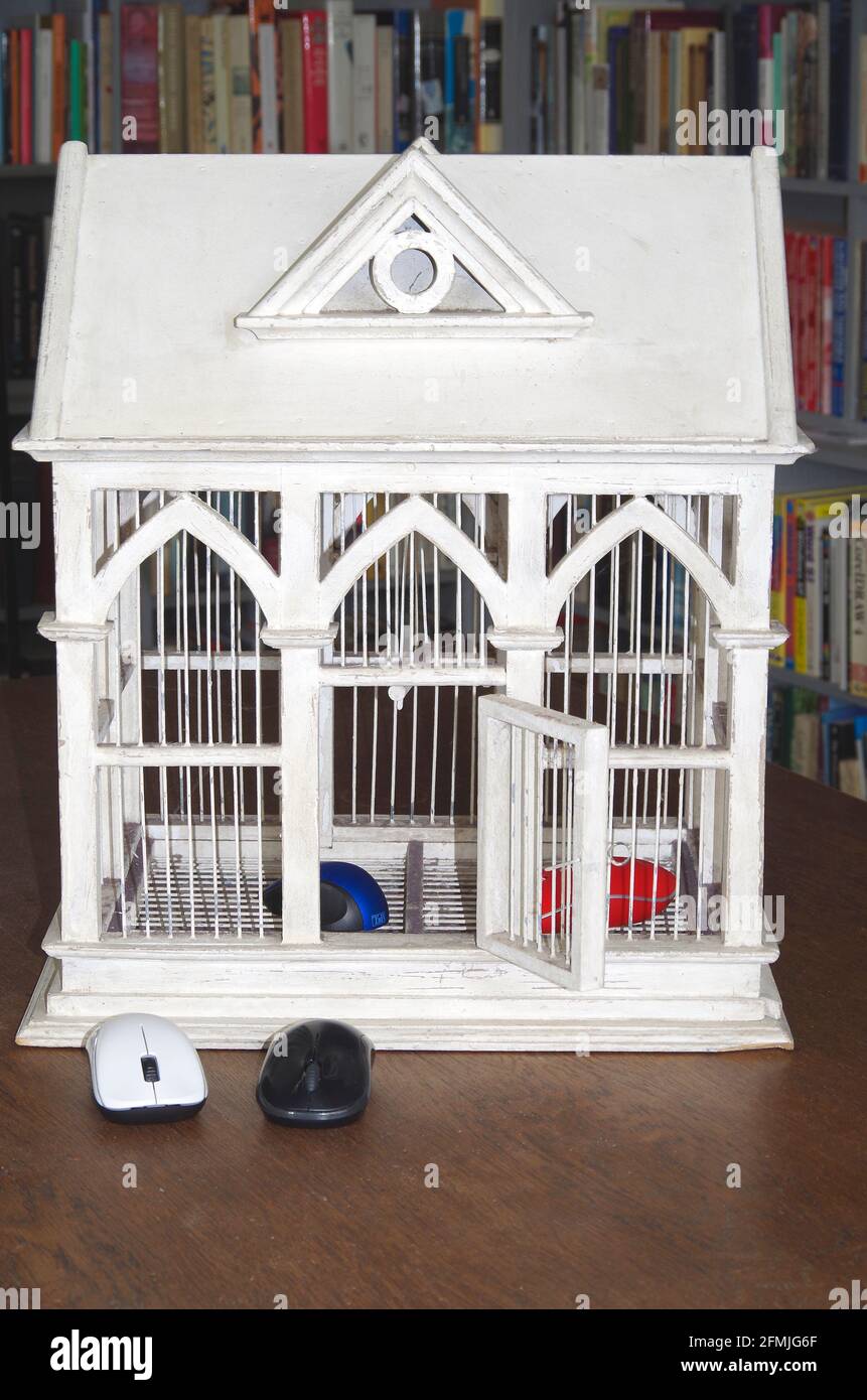 Une cage d'oiseau en bois de Gothicky peinte en blanc avec porte ouverte, l'oiseau a volé pour être remplacé par des souris d'ordinateur. Banque D'Images