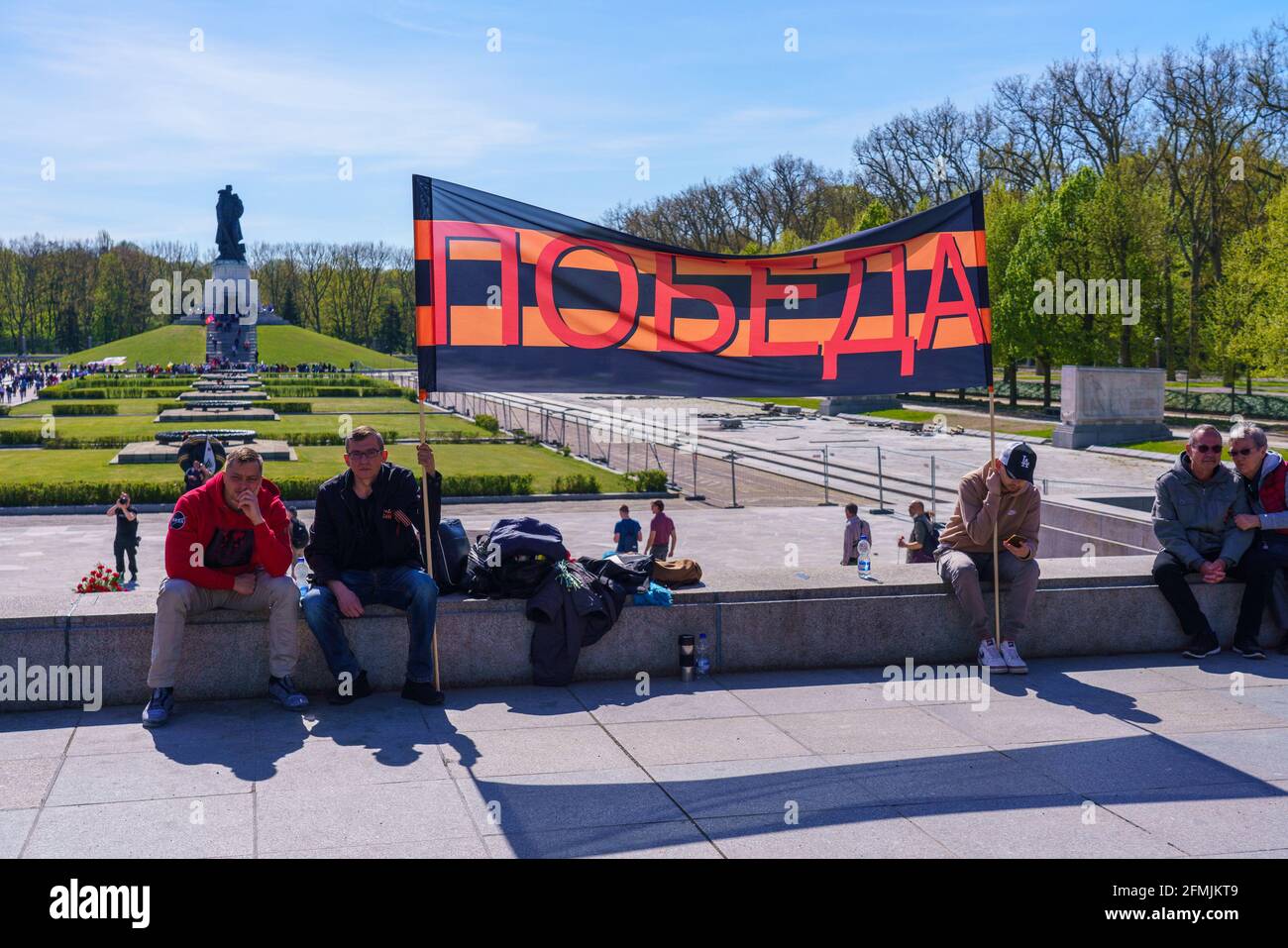 9 mai 2021, Berlin, au Mémorial de la guerre soviétique dans le parc Treptower (Treptower Ehrenmal), un mémorial et en même temps un cimetière militaire, de nombreux Russes et Allemands-Russes commémorent le 76e jour de la victoire à la fin de la Seconde Guerre mondiale avec de nombreux drapeaux colorés. Le mémorial a été érigé en 1949 sur les instructions de l'administration militaire soviétique en Allemagne pour honorer les soldats de l'Armée rouge qui sont morts pendant la Seconde Guerre mondiale Plus de 7000 des soldats morts dans les Schlaghs autour de Berlin sont enterrés ici. Sur la photo : visiteurs avec une bannière du ruban de Saint-George. | utilisation dans le monde entier Banque D'Images
