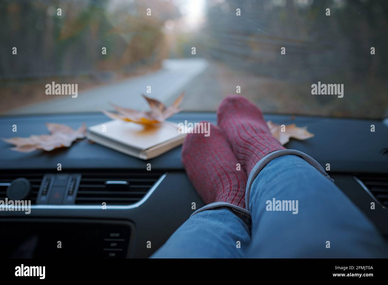 Femme pieds en chaussettes chaudes sur le tableau de bord de voiture . Le concept de liberté de mouvement. Week-end d'automne. Banque D'Images