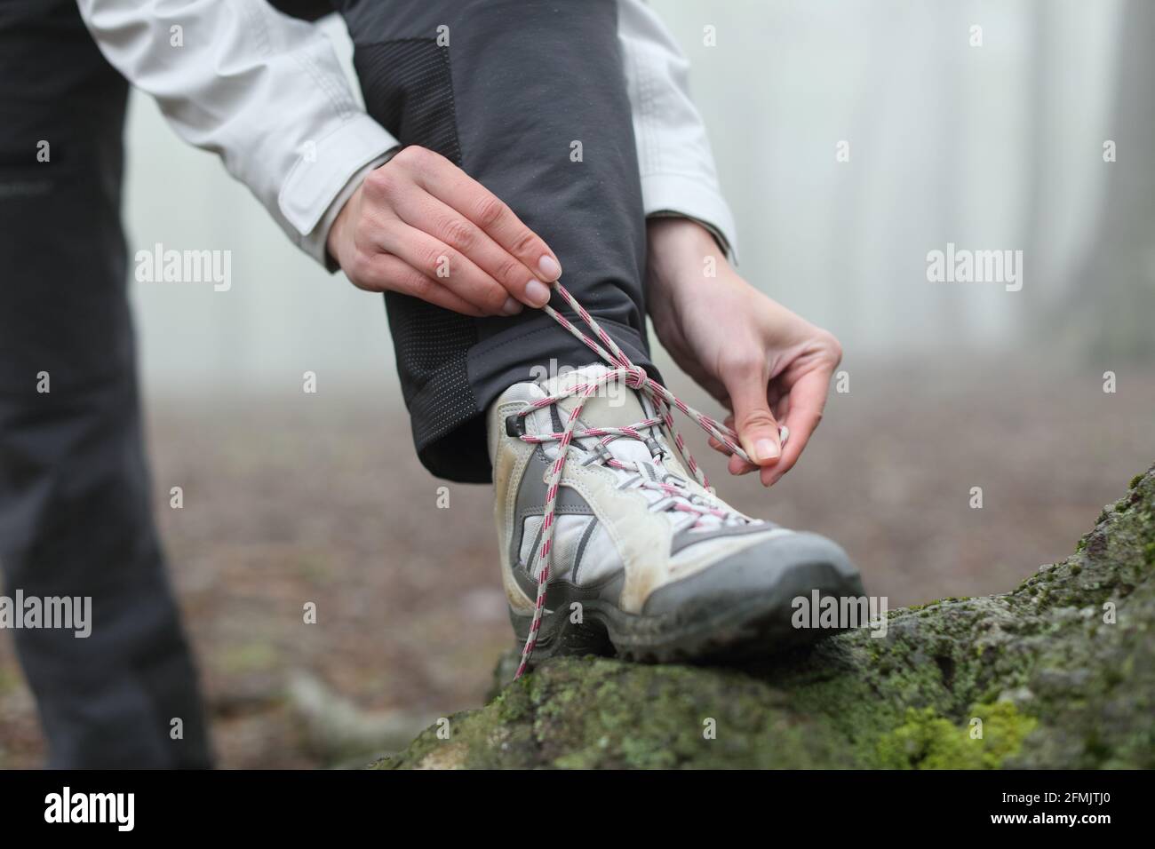 Gros plan sur les mains d'un randonneur qui enfile les lacets de bottes la montagne Banque D'Images