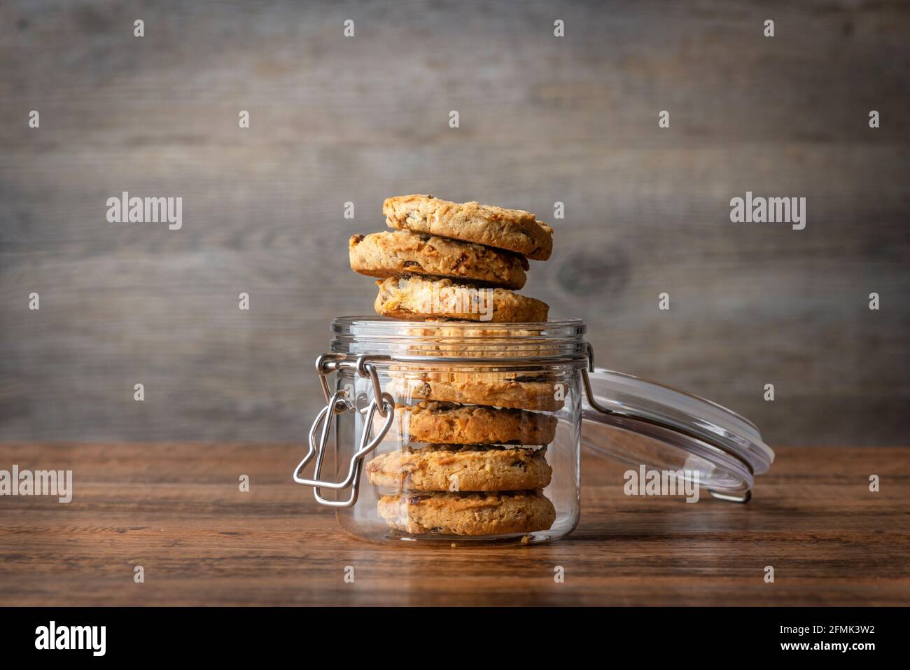 Pot à biscuits en verre avec des biscuits faits maison à l'avoine et au raisin sur une surface en bois. Banque D'Images