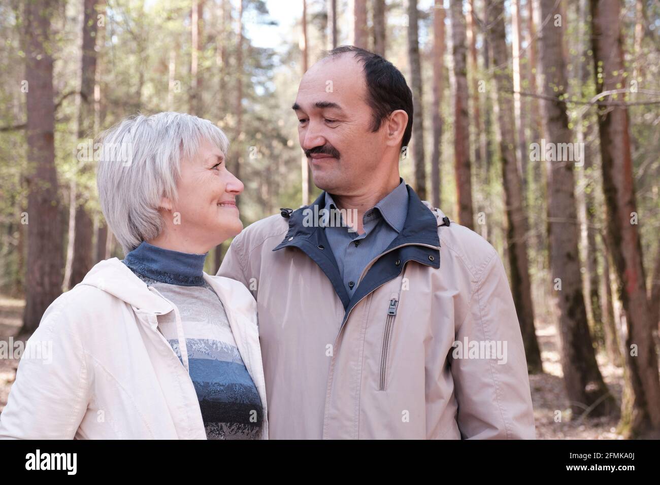 Couple interracial âgé vêque dans un parc forestier de printemps, souriant, regardant l'un l'autre. Gros plan Banque D'Images