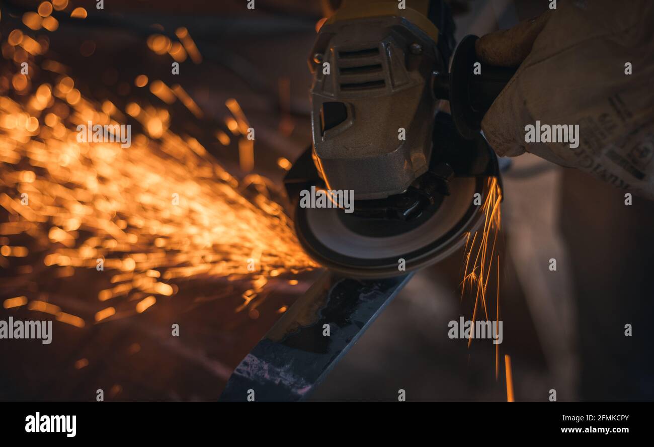 Travailler dans un morceau de fer avec une machine à meuler Banque D'Images