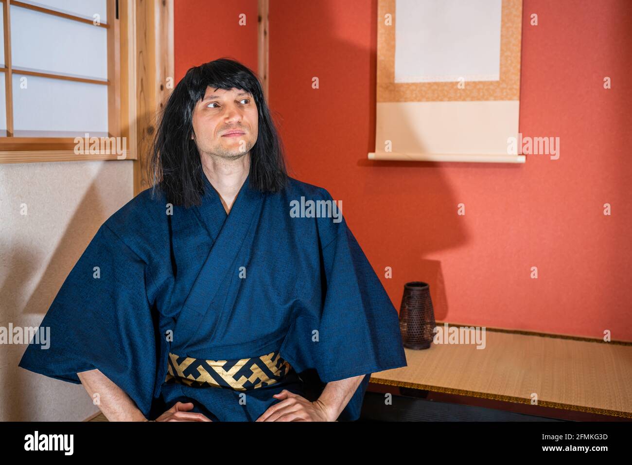 Portes en papier coulissantes traditionnelles au Japon avec homme en kimono costume et cheveux noirs assis à côté d'alcôve pendante rouleau de papier regarder Banque D'Images