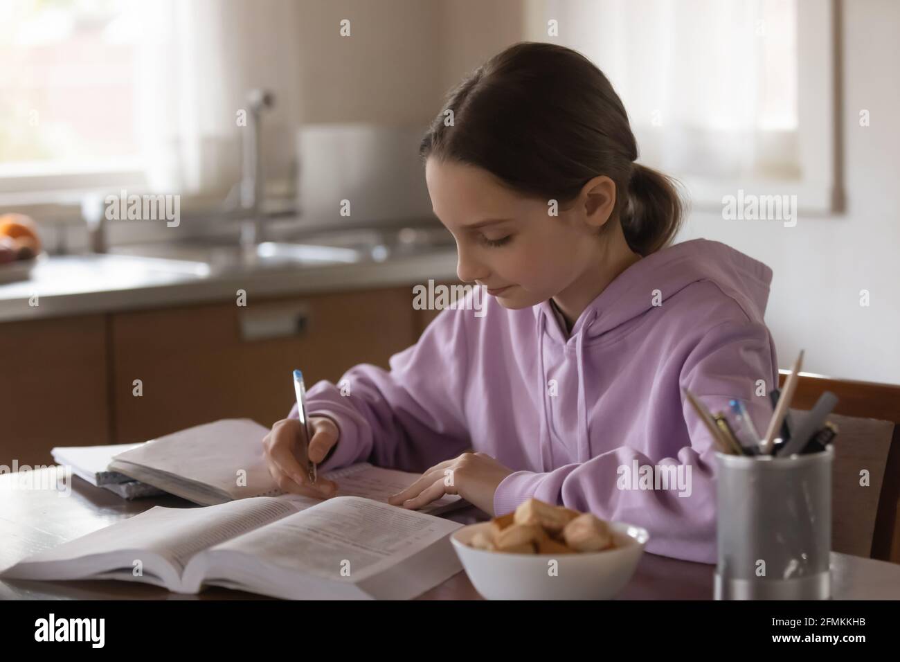 Jeune fille jeune fille ciblée étudiant seul dans la cuisine. Banque D'Images