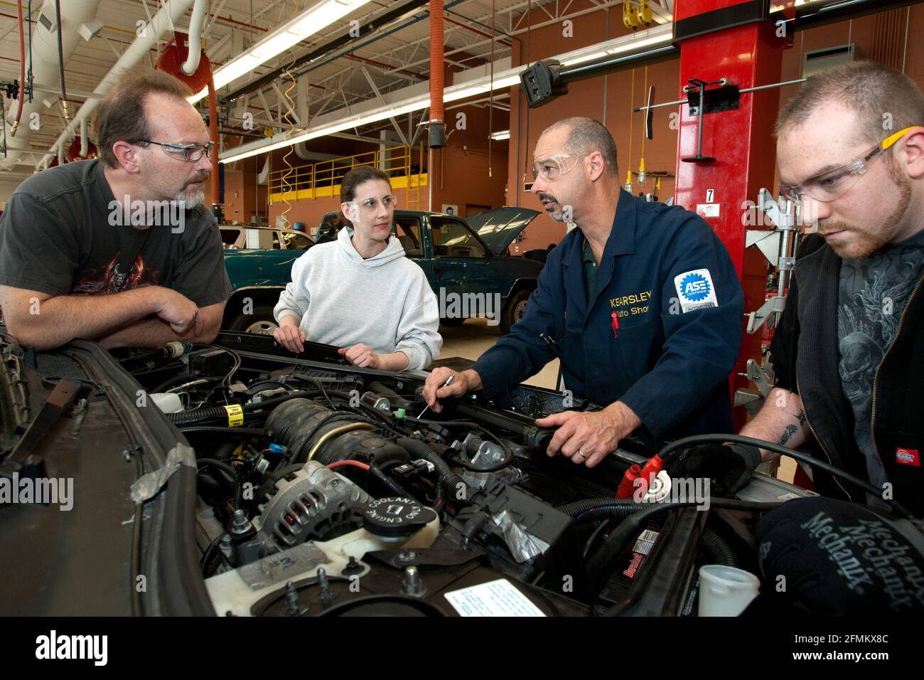 Les garçons du secondaire avec des instructeurs examinent un moteur dans la voiture classe professionnelle de réparation Banque D'Images