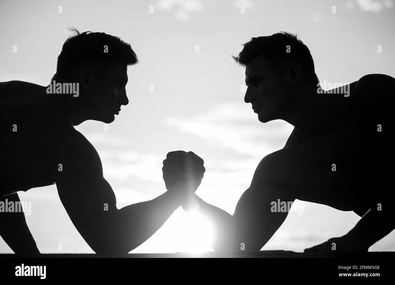 Rivalité, vs, défi, lutte de main. Coucher de soleil, lever du soleil. Hommes mesurant les forces, les bras. Deux hommes luttant. Silhouette de mains qui rivalisent Banque D'Images