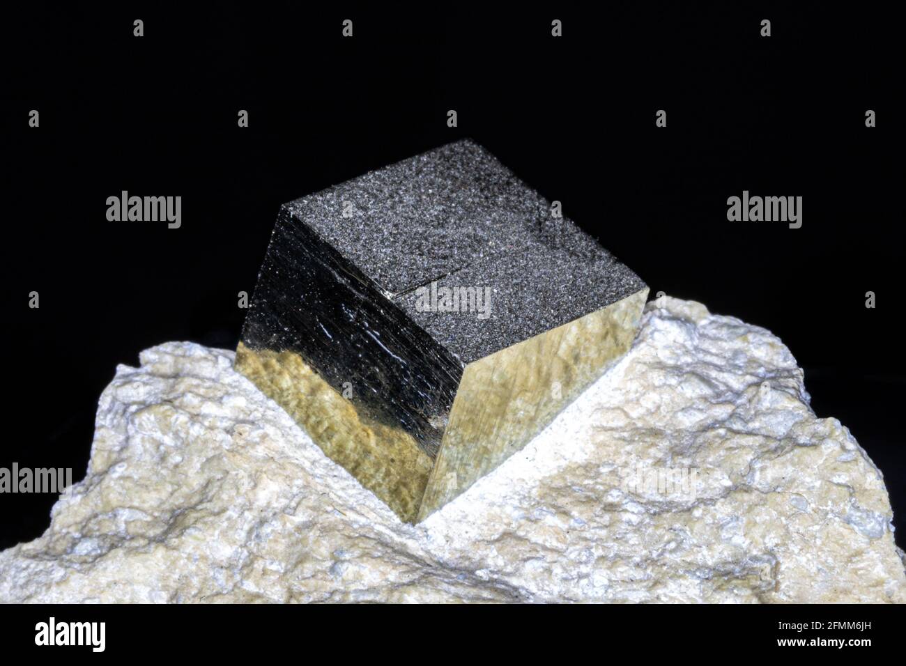 Pyrite de fer d'espagne; cristal cubique naturel dans la roche hôte. Les côtés métalliques jaunes se reflètent avec une finition miroir. Banque D'Images