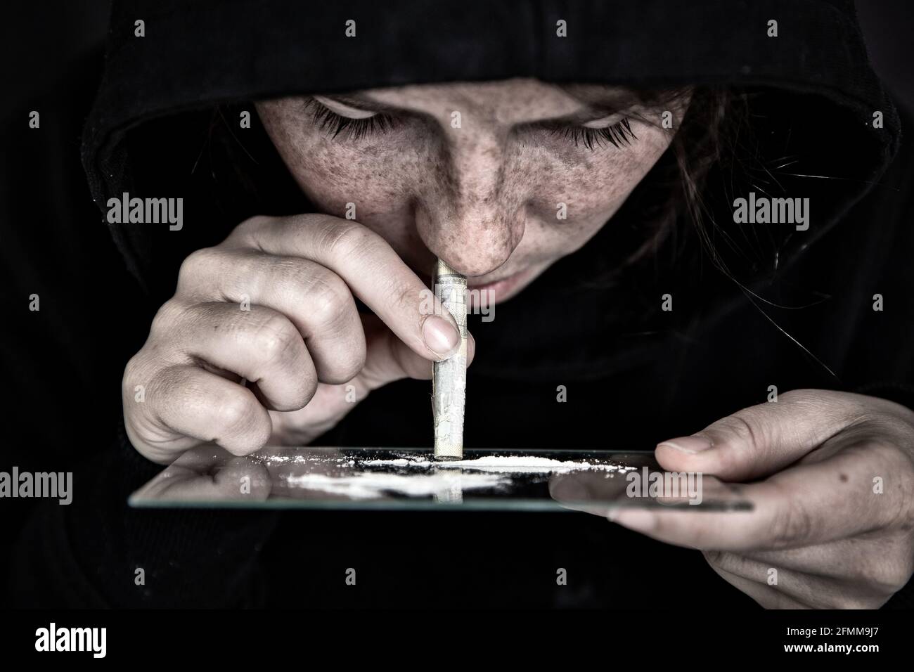Drogue Addict renifler et ronfler la cocaïne, vitesse, héroïne ou autre drogue avec l'argent roulé sur le miroir avec fond sombre, toxicomanie, drogues, déprimé Banque D'Images