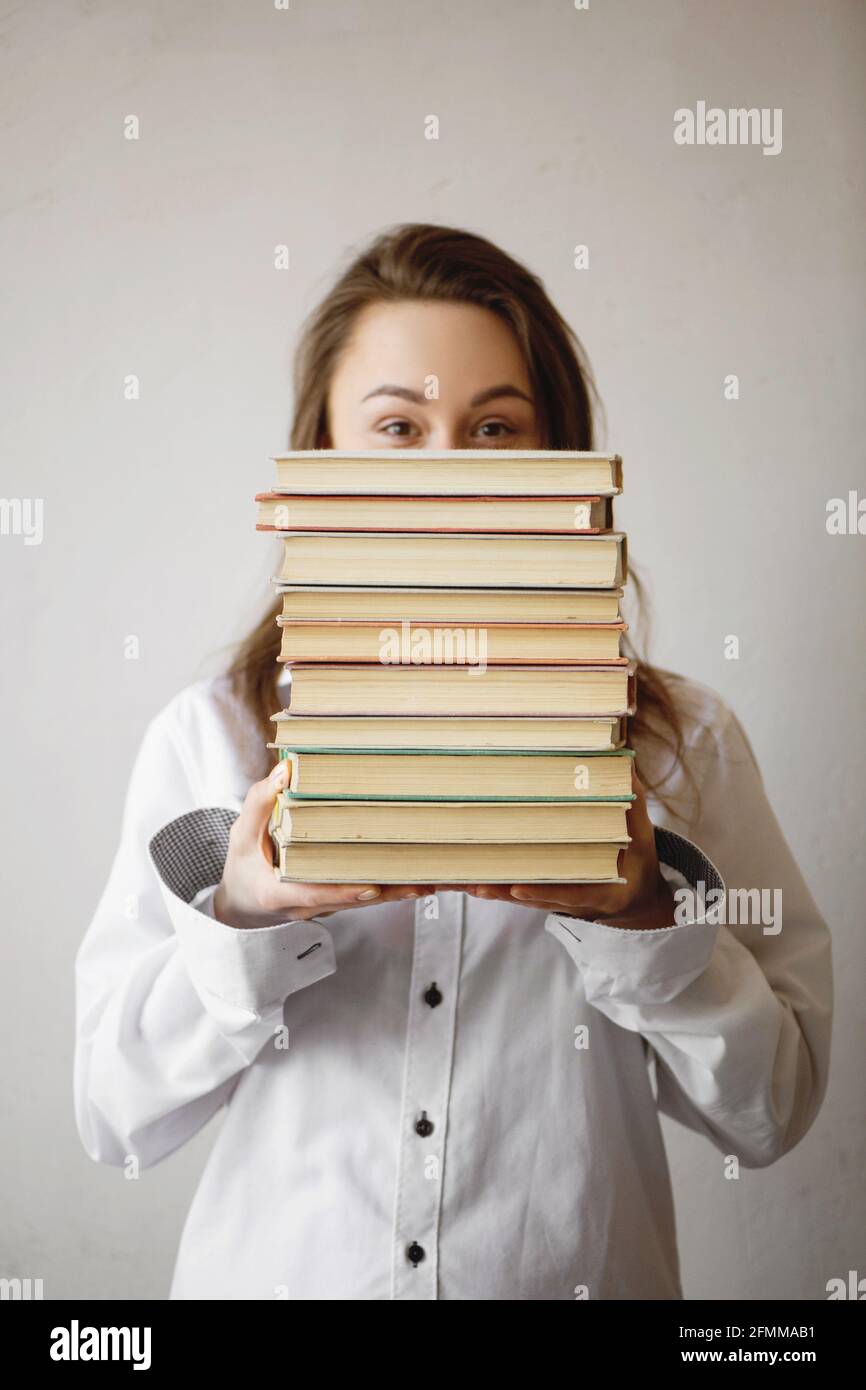 Portrait d'une femme mignonne tenant une pile de livres. Banque D'Images