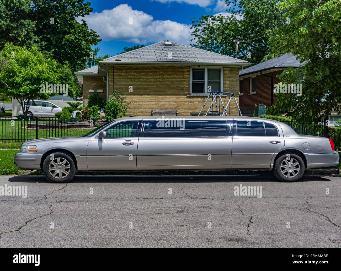 Limousine argentée garée sur le trottoir d'un quartier résidentiel Banque D'Images