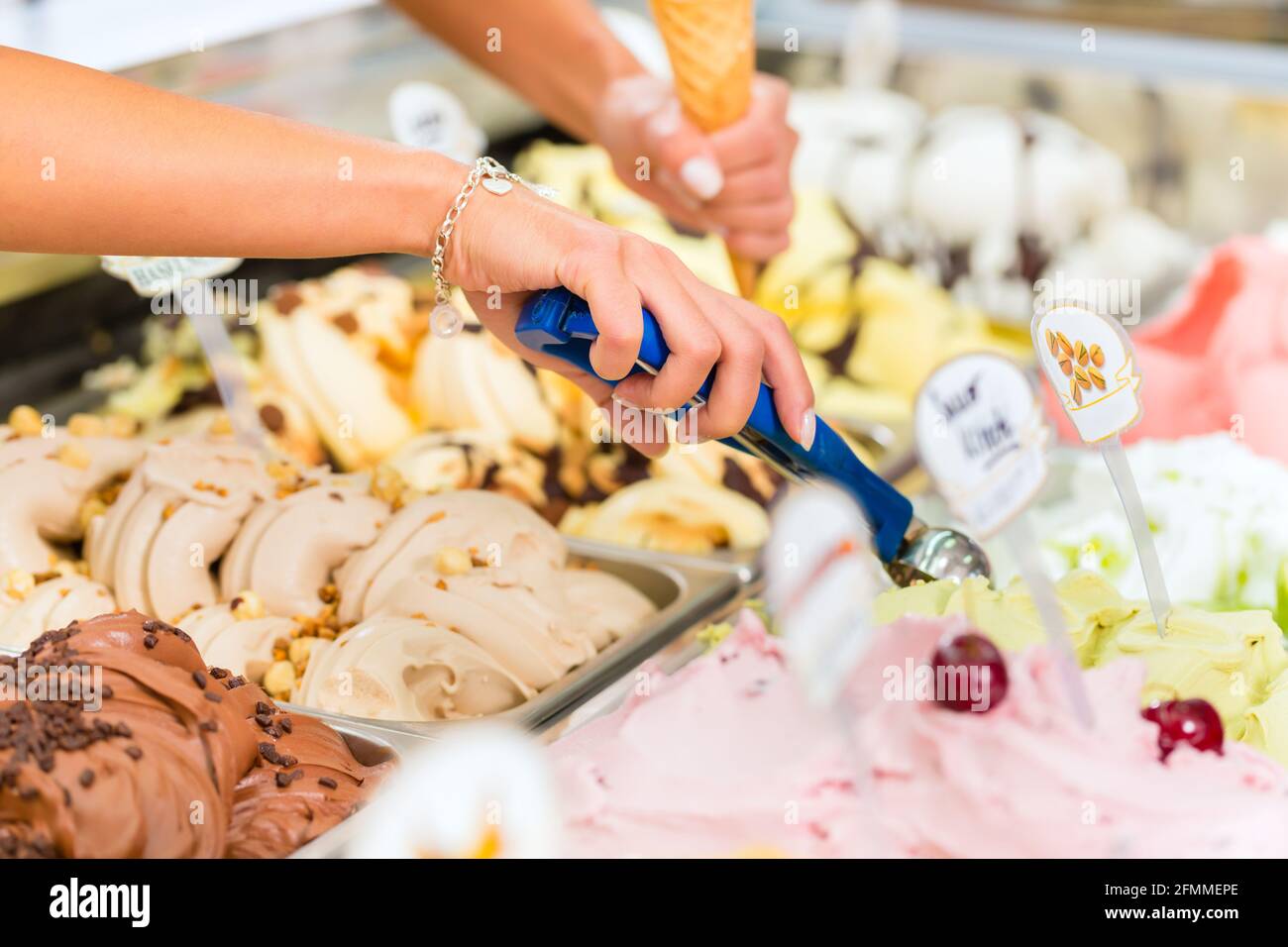 Jeune vendeuse dans un glacier prend une boule de crème glacée Banque D'Images