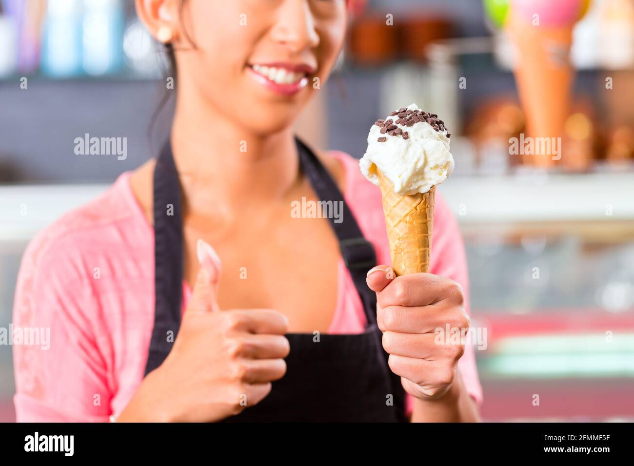 Jeune vendeuse asiatique dans un glacier avec cornet de crème glacée Banque D'Images