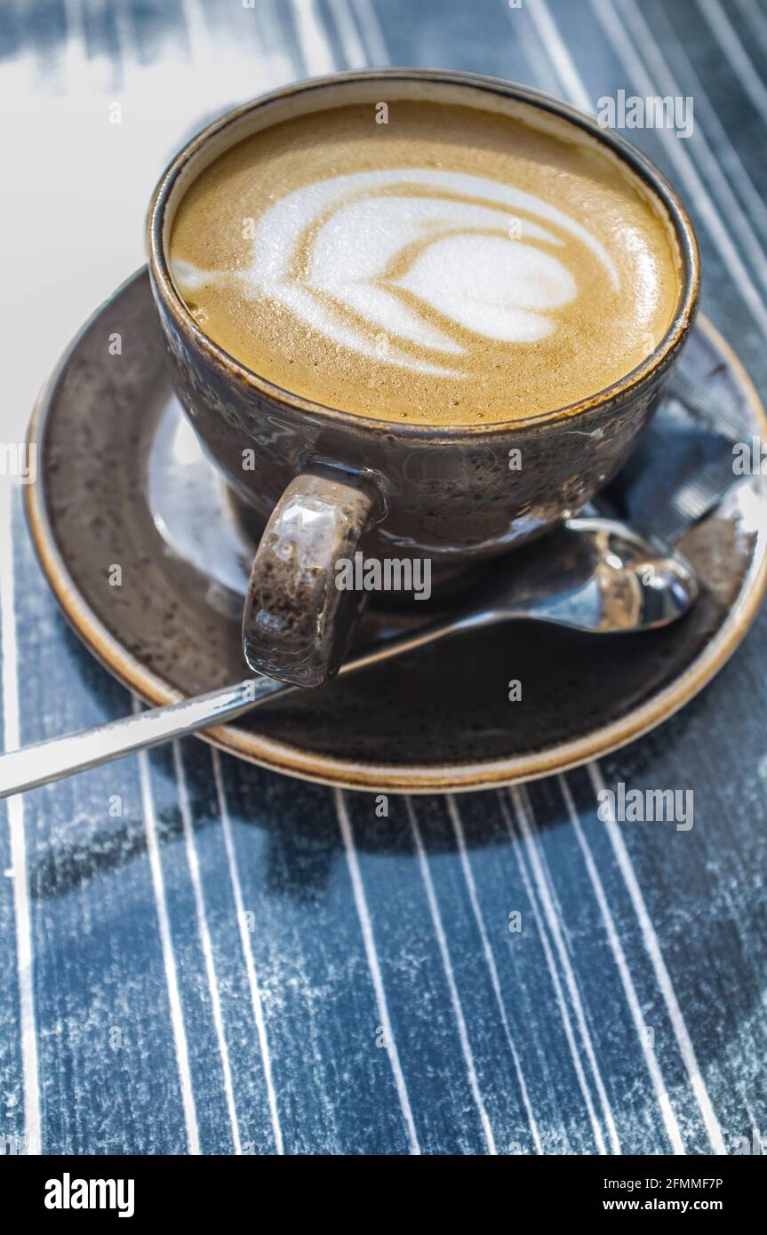 Tasse de café frais avec motif fleuri en mousse. Table en bois sombre comme arrière-plan Banque D'Images