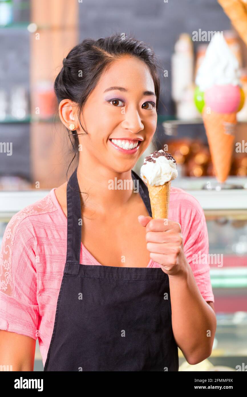 Jeune vendeuse asiatique dans un glacier avec cornet de crème glacée Banque D'Images