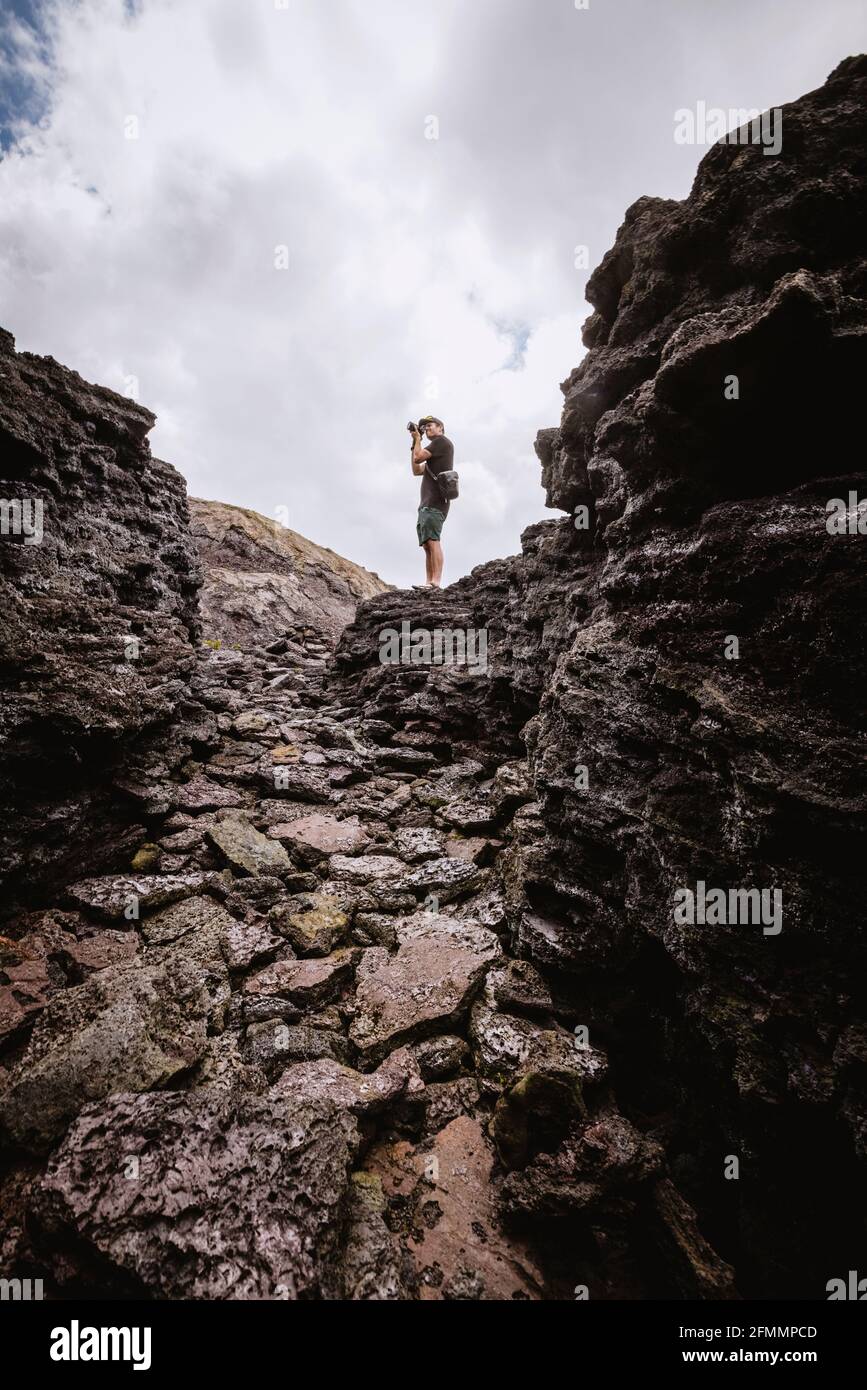 Man prend la photo parmi les rochers du parc national du volcan d'Hawaï Banque D'Images Man prend la photo parmi les rochers du parc national du volcan d'Hawaï Banque D'Images