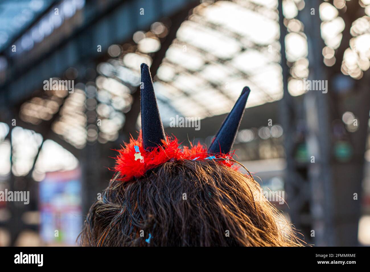 Carnaval à la gare principale de Cologne. De derrière vous pouvez voir une femme avec des cornes de diable sortir de sa tête de confetti fiery Banque D'Images