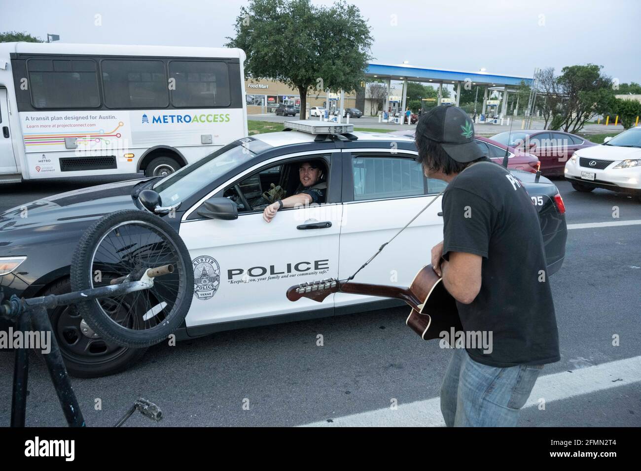 Le musicien et le handyman Douglas Crawford accueille un policier d'Austin alors qu'il lui fait jouer sa guitare pour changer près de son camp, à l'angle de Ben White Blvd. Et de South Congress Avenue à Austin, au Texas, où il a vécu plus d'un an. Crawford, 60 ans, dit qu'il reste à lui-même et qu'il ne s'inquiète pas de la nouvelle répression d'Austin contre les sans-abri et de l'interdiction de camper à partir de mardi. ©Bob Daemmrich Banque D'Images