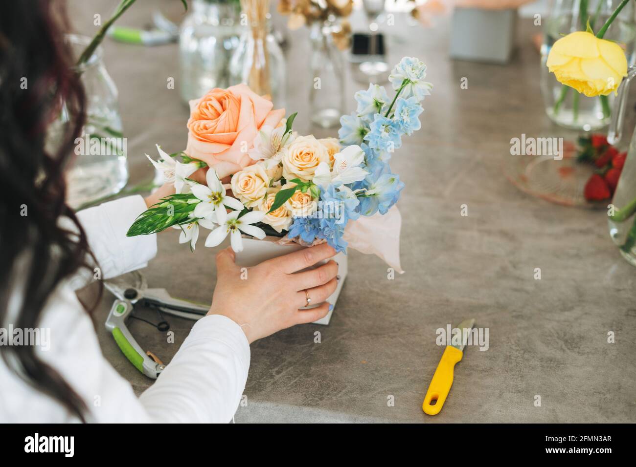 Jeune fleuriste blanc avec bouquet de fleurs en boîte dans un fleuriste, petite entreprise locale propriétaire. Jeune femme millénaire de succès élégante sur le Banque D'Images